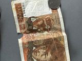 a small piece of paper with a picture of a man on it next to a coin