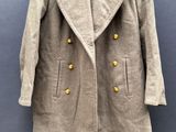 manteau en laine avec des boutons dorés, suspendu à un cintre sur fond bleu