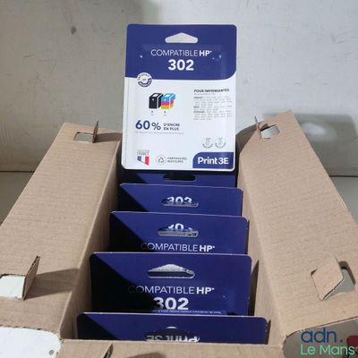 Quatre cartouches d'encre se trouvent dans une boîte en carton posée sur une table