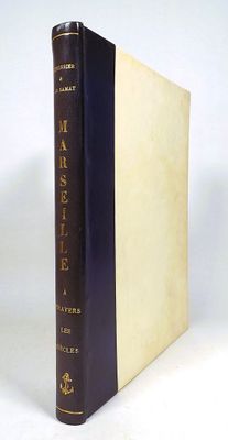 an old book with a black cover sitting on top of a white table