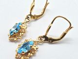 pair of gold tone earrings with blue crystal stones on them