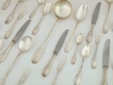 a lot of silver spoons and forks laid out on a table
