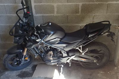 une moto noire garée dans un garage, près d'un mur de briques
