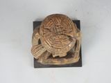 a small carved turtle sitting on top of a wooden block