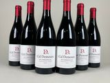 six bottles of red wine are lined up on a table