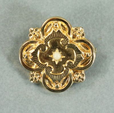 une image d'une broche en or avec une perle au centre