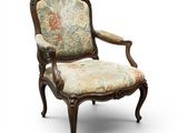 une vieille chaise dont l'assise est recouverte d'un tissu à motifs floraux