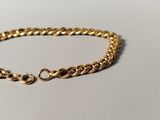 a close up of a gold chain bracelet on a white surface