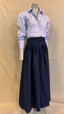 Le mannequin porte une chemise bleue et blanche et une jupe noire.