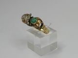 a close up of a gold ring with a green stone on it