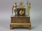 a small clock with a statue on top of it