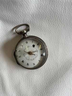 une montre de poche en argent avec des chiffres romains