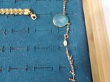 a gold chain with a blue stone and a gold chain with a blue stone and a gold chain with a blue stone and a gold chain with a blue