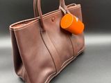 une photo d'un sac à main marron avec une étiquette orange dessus