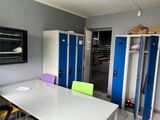 brightly colored lockers line the walls of a room with a white table and yellow chairs