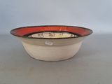 a red and black bowl sitting on a white table