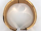 a close up of a gold bracelet on a white surface