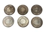 a group of six silver coins on a white background