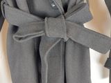 Le manteau est gris et est muni d'une ceinture