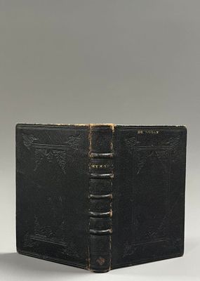 an old black book sitting on top of a table next to a white wall