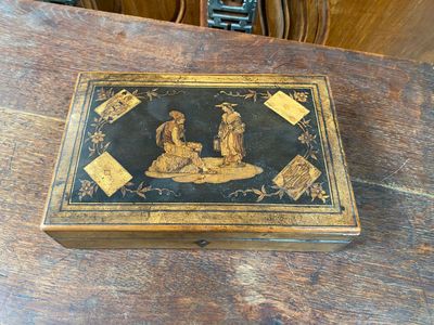 une boîte en bois décorée d'une peinture, posée sur une table