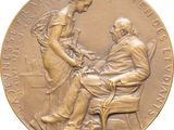 an image of a bronze medal depicting a man and a woman sitting at a table