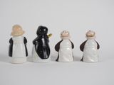 four ceramic penguins are lined up in a row on a white surface