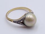 an image of a white pearl and diamond ring on a white surface
