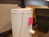 a white bucket sitting on the floor next to a trash can