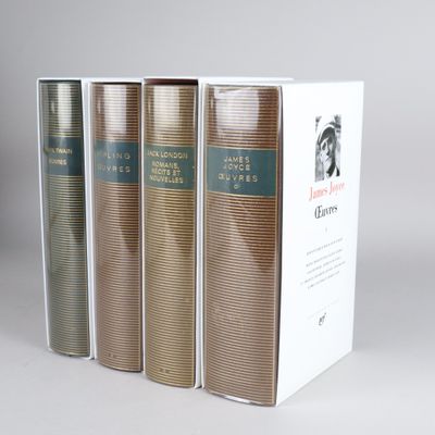 three books in a row on a white surface with a gray background