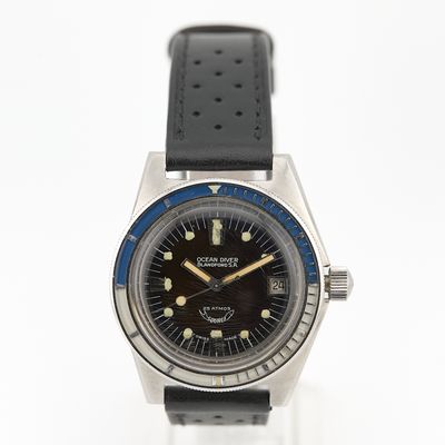 une image représentant une montre noire et bleue posée sur une surface blanche