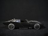 a black toy car that is sitting on a black surface