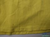 yellow t - shirt with white stitching on it sitting on a table