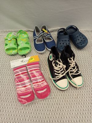 Plusieurs paires de chaussures et de chaussettes d'enfants sont disposées par terre.
