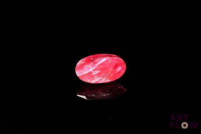 an image of a red stone sitting on top of a black surface