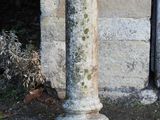a stone pedestal with a bird on it in front of a building