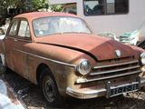 rusted old car parked in front of a trailer in a yard