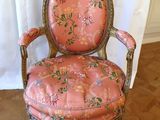 an old chair with a pink upholstered seat sitting on a wooden floor