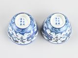 pair of blue and white vases with birds on them on a white surface