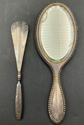 a silver mirror and a silver spoon on a table