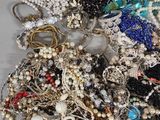 a pile of jewelry on a table with a wine glass