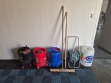 several buckets, a broom, and a mop on the floor in a room