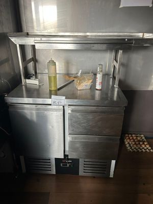 une petite cuisine avec un plan de travail en inox et un réfrigérateur