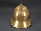 an antique brass fireman ' s helmet on a black background