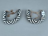 une paire de boucles d'oreilles ornées de motifs noirs et blancs sur un fond gris
