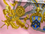 a pink scarf with a picture of a coat of arms on it