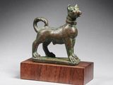 une figurine en bronze représentant un chien, posée sur un socle en bois