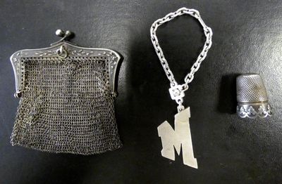 un porte-monnaie en argent et un dé à coudre en argent posés sur une table