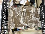 un panier noir rempli de livres et de papiers posé par terre