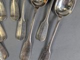 six silver spoons are arranged in a circle on a gray surface
